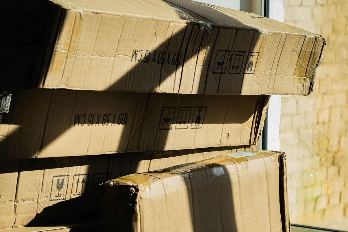 Corporate relocation car shipping: stacked moving boxes in sunlight beside a window, ready for a job move
