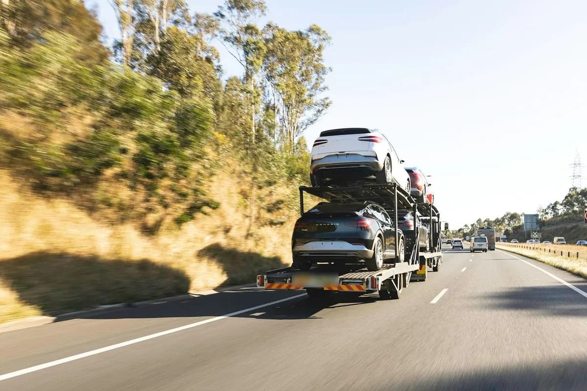 How long does it take to ship a car: a loaded open car hauler driving down a long interstate