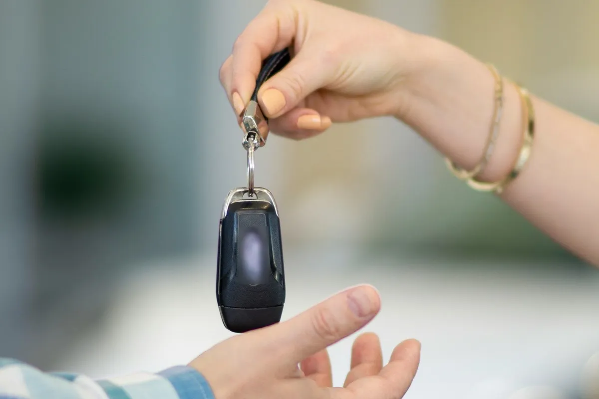 Seller preparing to ship a car to a buyer: a car key handed from one person to another