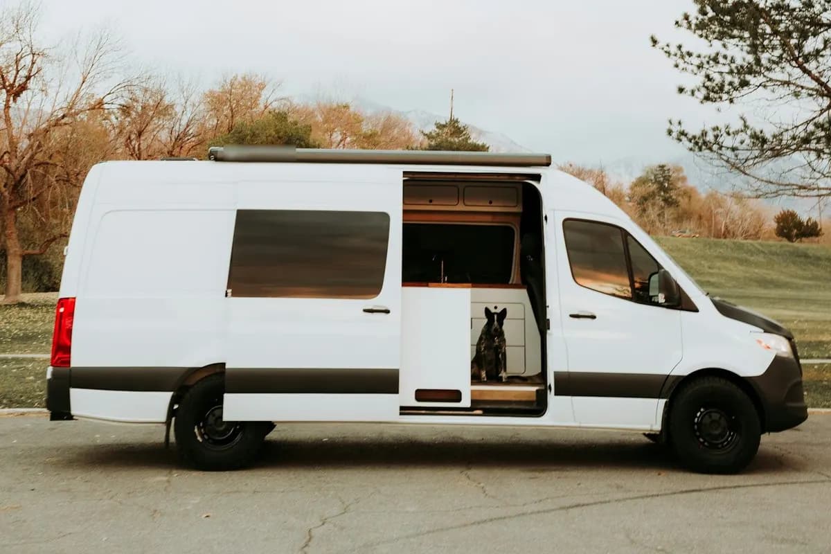 Sprinter van shipping: a white high-roof camper van conversion parked side-on with its sliding door open